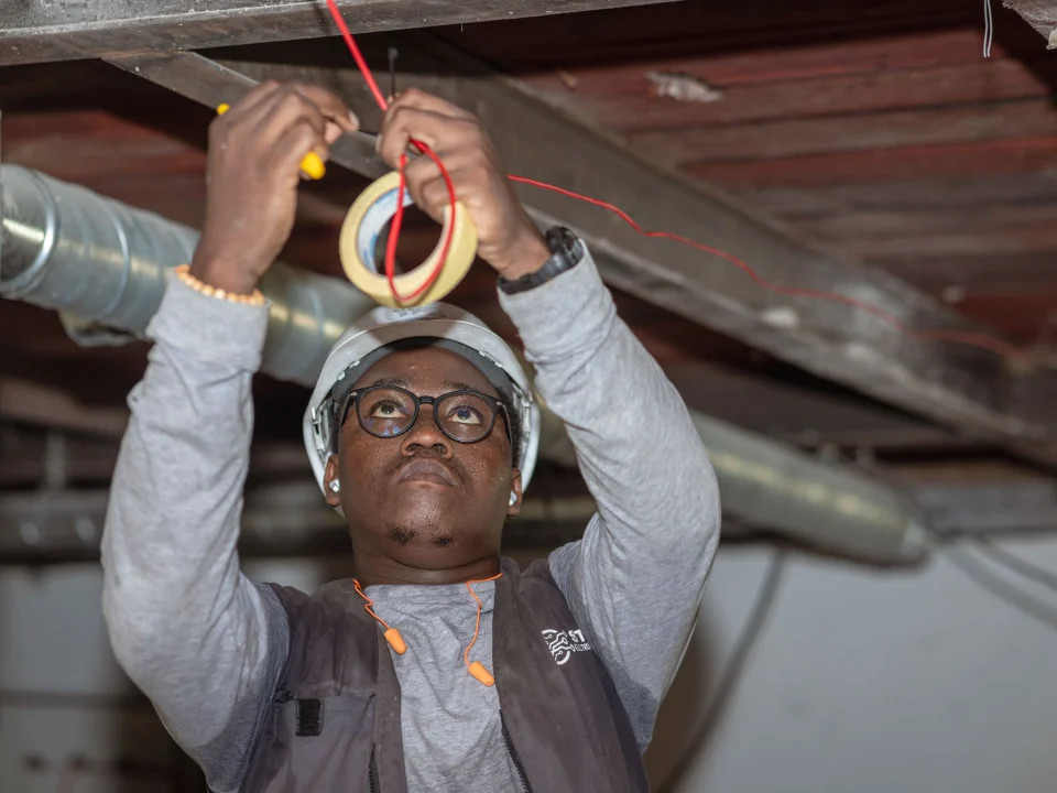 Electrical technician in a hard hat working on overhead cabling