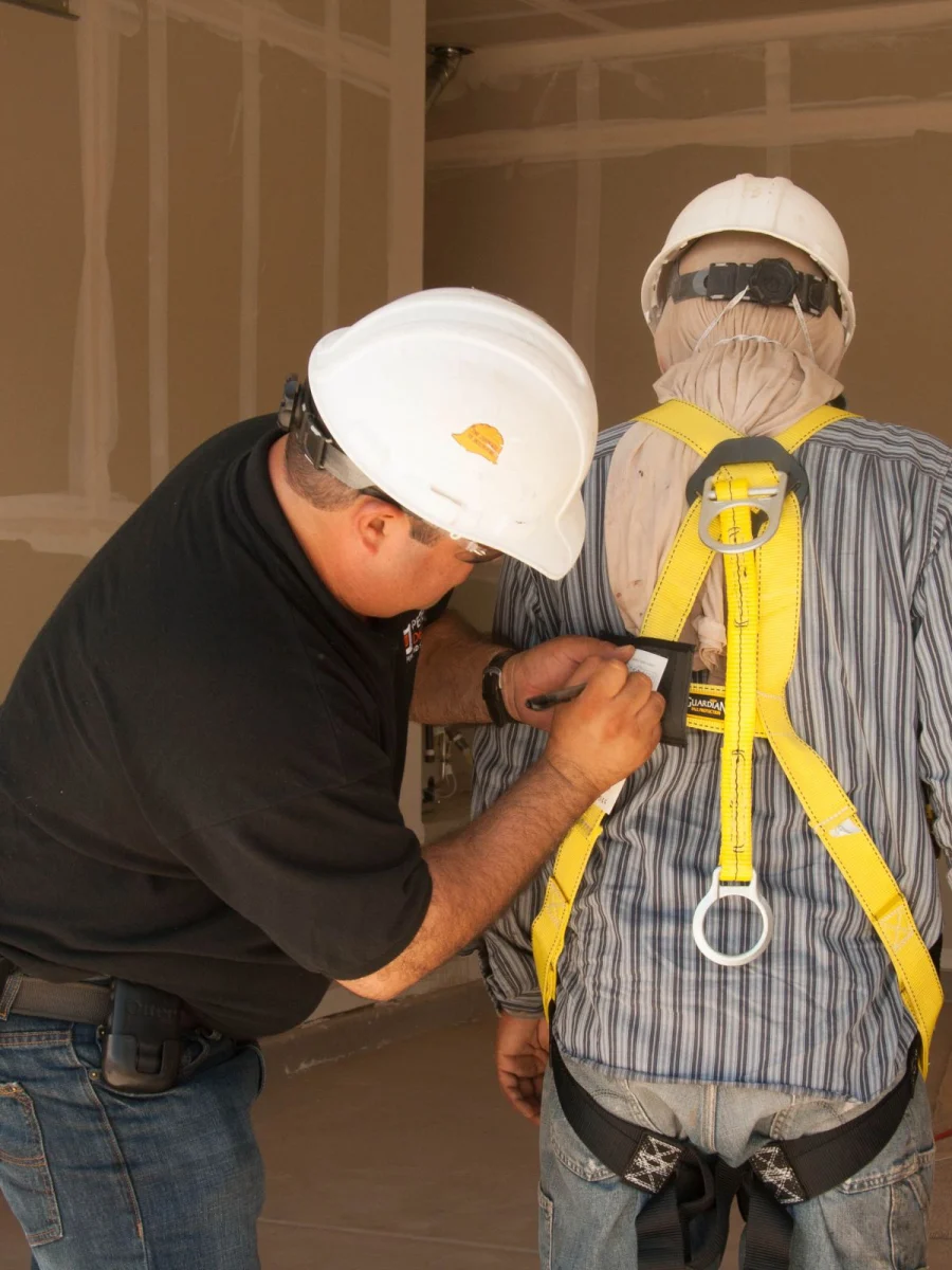 Supervisor checking a worker's fall-arrest harness before work at height