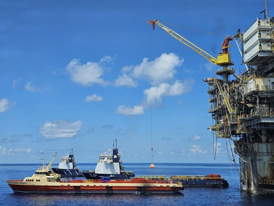Offshore platform crane lifting cargo to a supply vessel